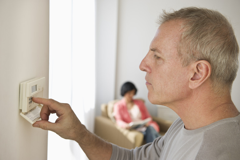 USA, New Jersey, Jersey City, Mature man adjusting room temperature, while woman is sitting in background