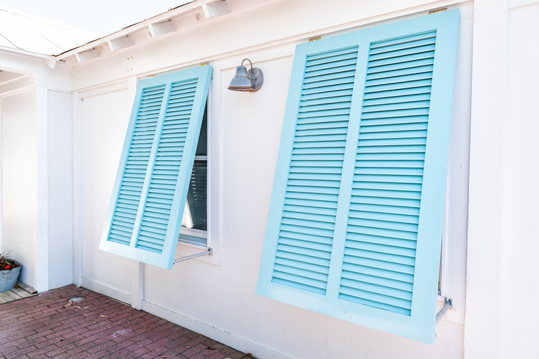 Pastel turquoise blue colorful hurricane window shutters closeup architecture open exterior of house in Florida beach home during sunny day, painted