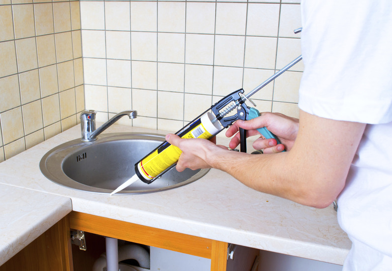 Caulking gun putting silicone sealant to installing a kitchen sink