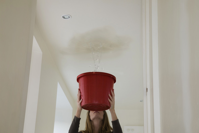 woman holding out a bucket to stop a roof leak