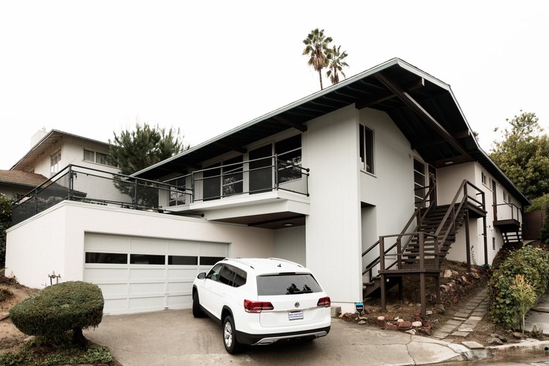 White home with large overhanging eaves with white car in driveway