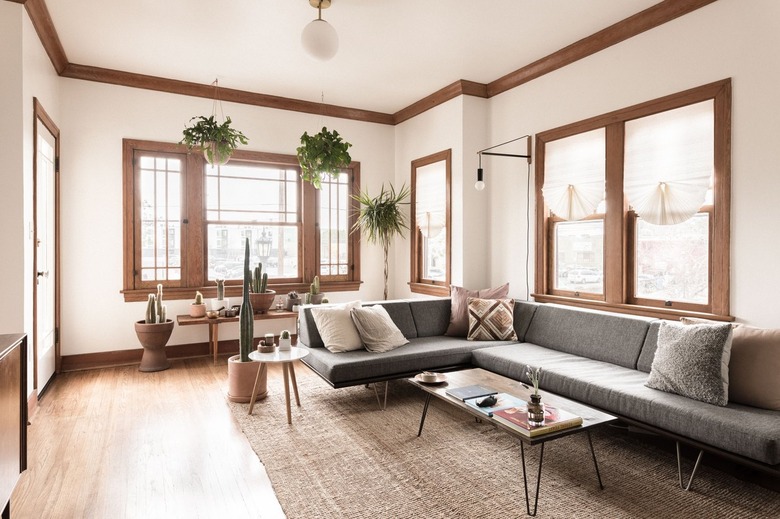 minimalist living room with grey couch, wooden coffee table and white walls