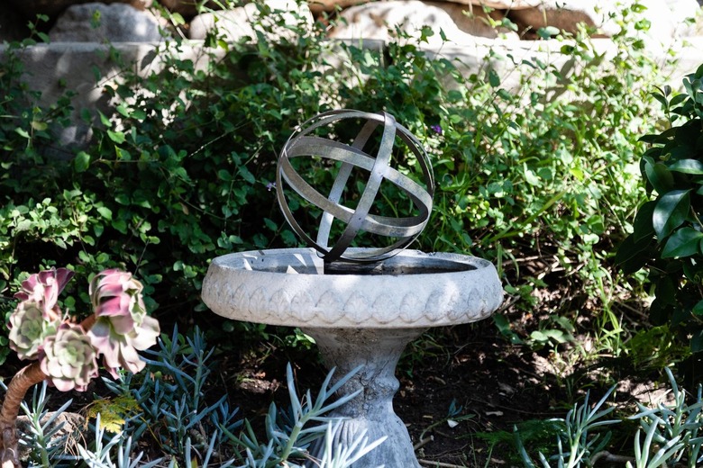 Small decorative garden fountain with bushes.