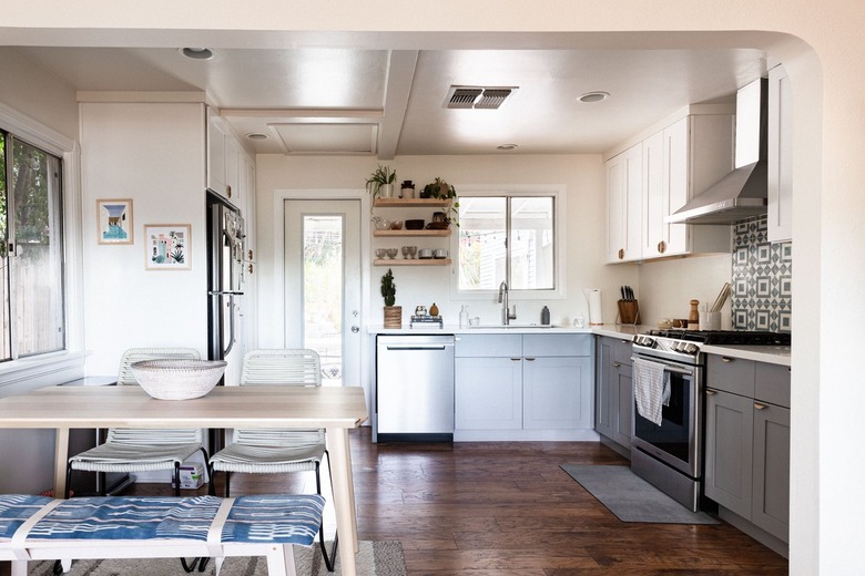 A minimalist kitchen with white walls, gray cabinets and dark wood floor