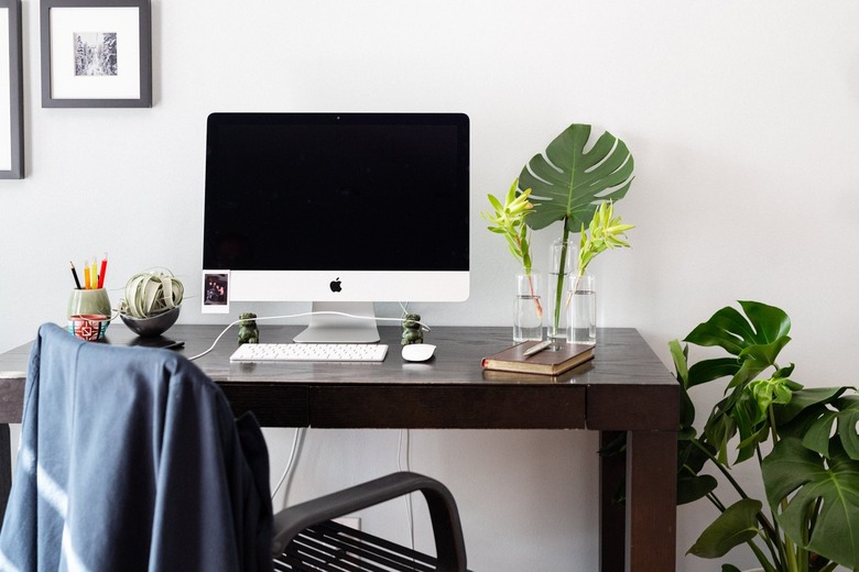 mac desktop on dark wood desk with black desk chair