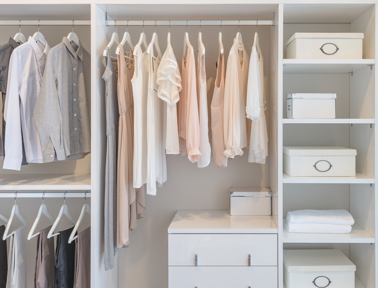 clothes hanging on rail in white wardrobe