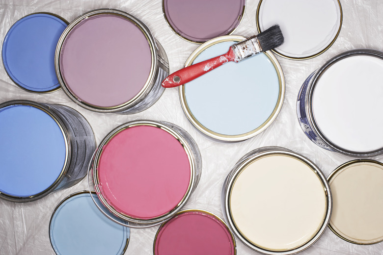 Paintbrush balancing on open tins of paint, overhead view, close-up