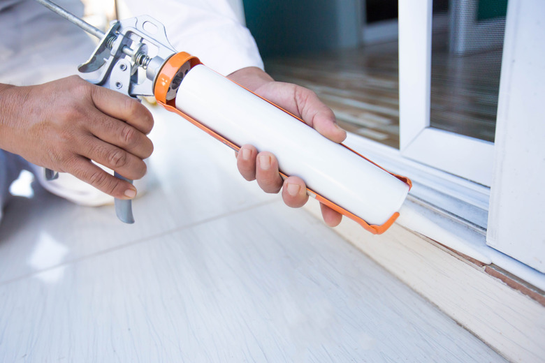 Construction workers install doors - windows and use silicon and sealant.