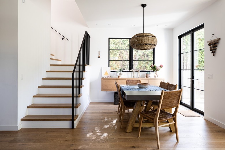 Dining room with white walls, wood furniture and flooring with staircase