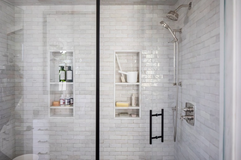 Glass door shower with gray wall tiles and shower niches.