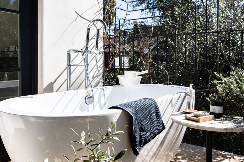 A bathtub on a balcony surrounded by plants.