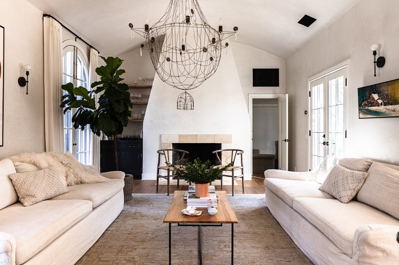 A white walled living room with white sofas and a chandelier