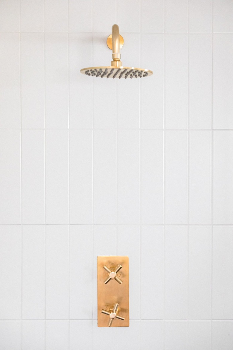 Gold shower head and white tile wall