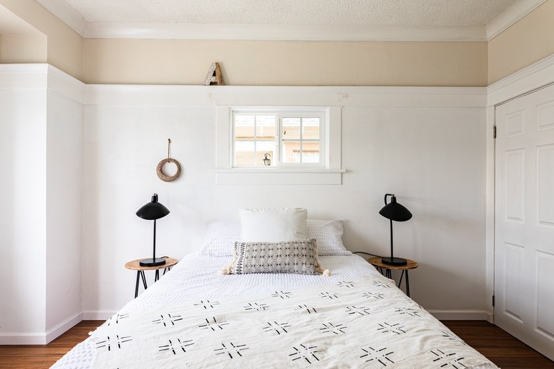 Boho bedroom with black table lamps, white walls and wood floors