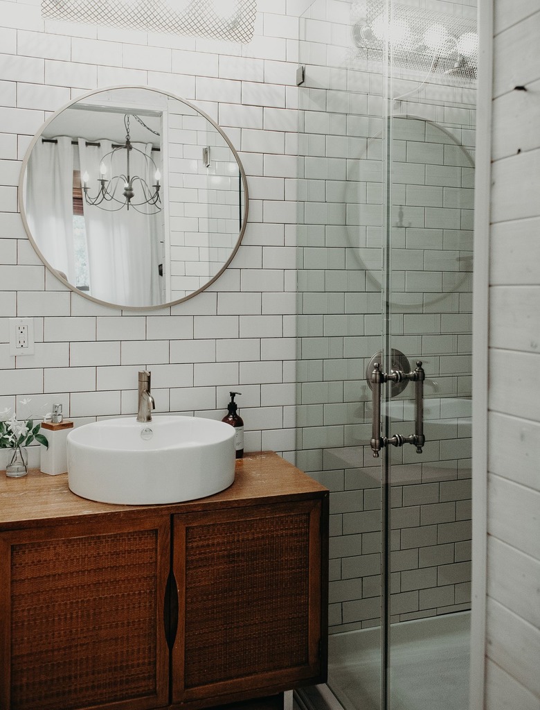 White tiled bathroom with wood vanity and glass door shower