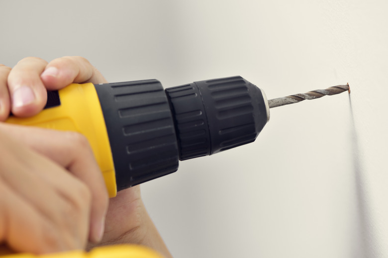 young man making a hole in a wall with a drill