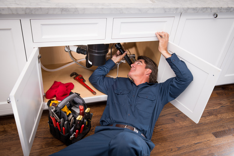 Plumber at work under kitchen sink.