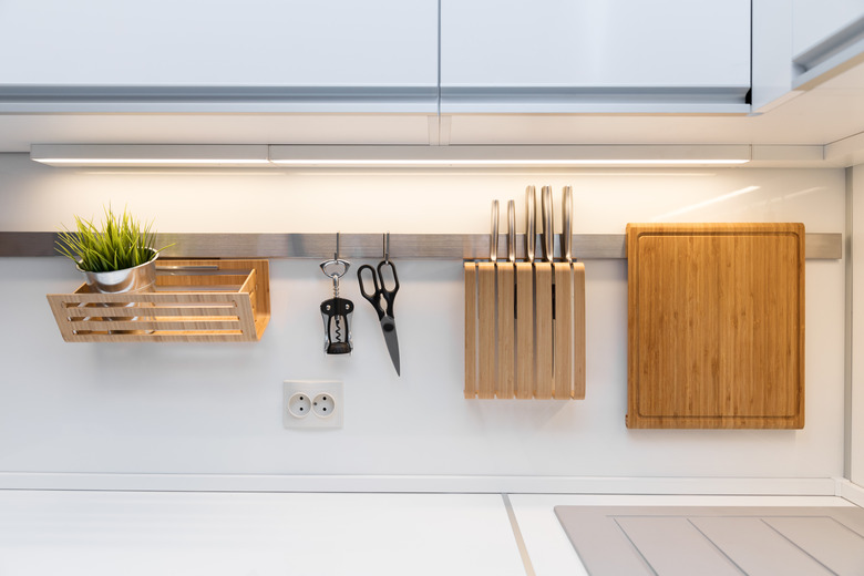 kitchenware hanging on the rail in the white glossy kitchen