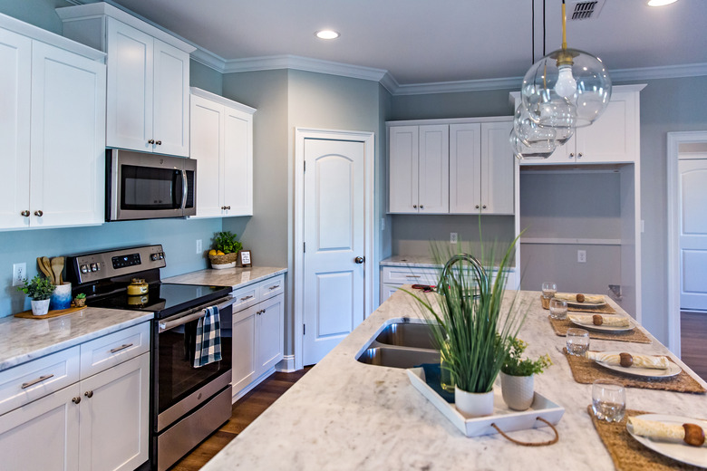 Open floor plan kitchen in a new construction empty house that has just been completed with white cabinets, pendant lighting, a bar area and hardwood floors