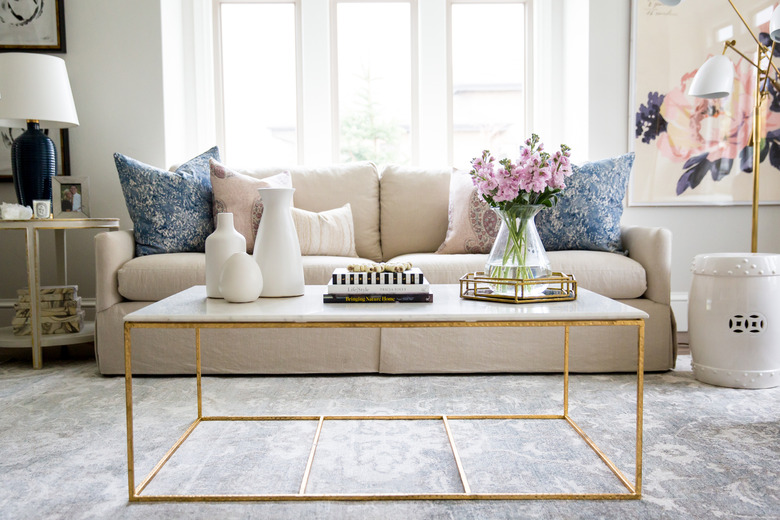 Blue floral carpet colors in traditional living room with marble coffee table and beige couch