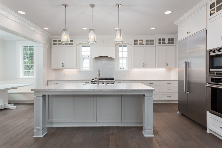 beautiful kitchen in new luxury home with island, pendant lights, and hardwood floors