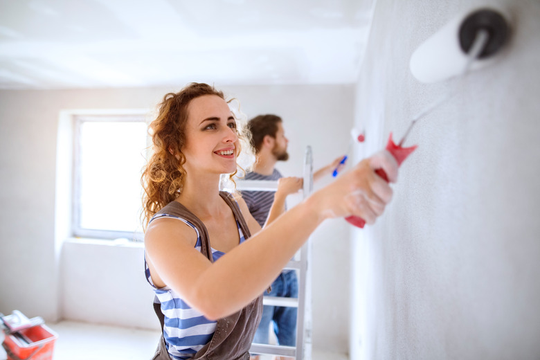 Young couple painting walls in their new house.