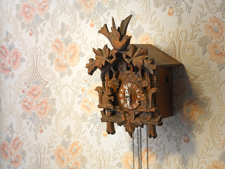 Vintage wooden cuckoo clock over a rose-pattern wall