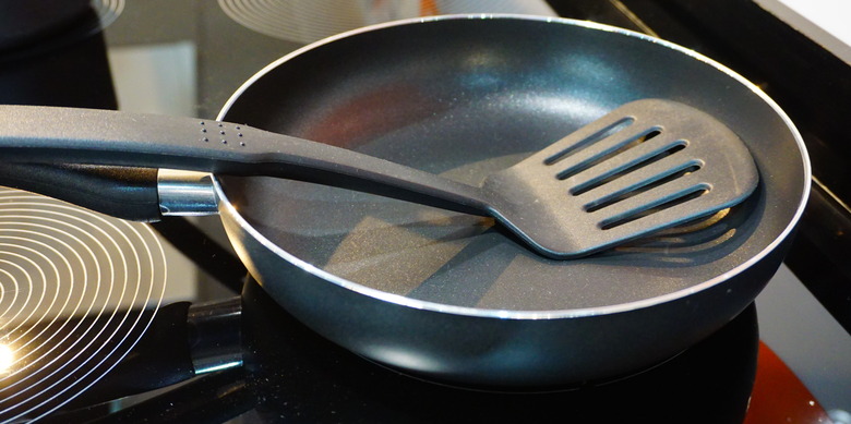 Metal black frying pan with a non-stick coating on electric stove