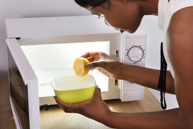 Human Hand Putting Sliced Lemon In Bowl