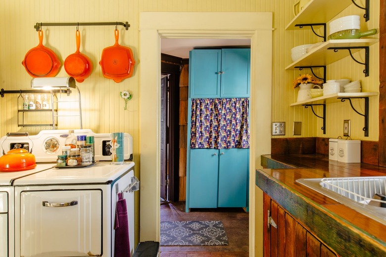 A colorful, vintage kitchen with yellow walls, retro stove and orange-blue accents