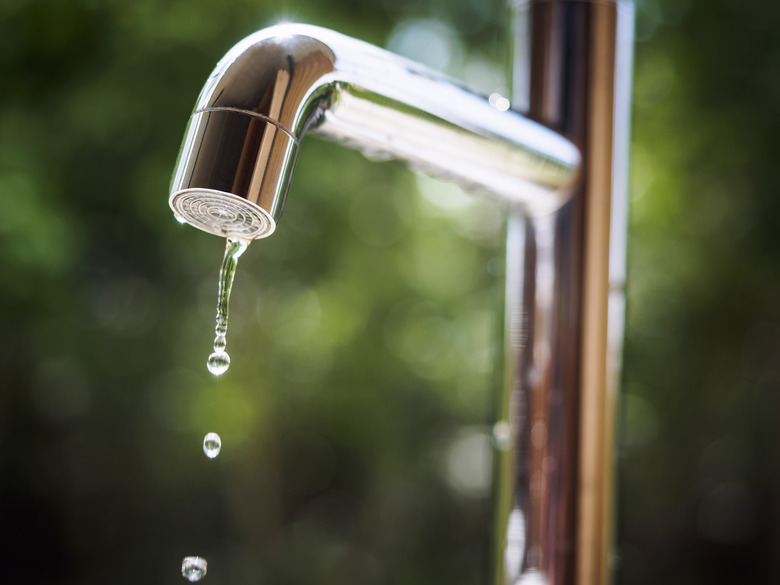 Water tap with water drop outdoor green park background