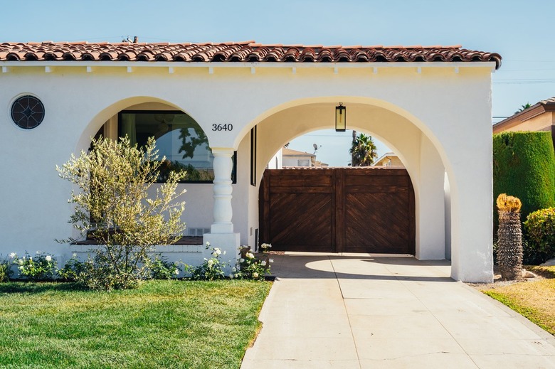 Spanish house, front yard, lawn, concrete driveway, arched entry, wood gate.