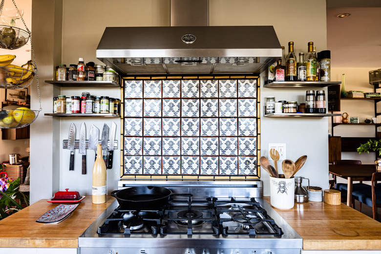 view of kitchen stove, accent backsplash and range hood