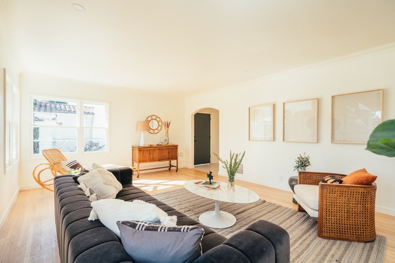 Living room with couch, accent chair, wall art, and rug, in a California-bohemian style.