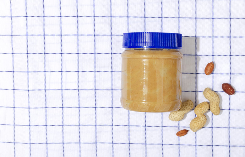 Top view of checkered tablecloth and jar full of peanuts on it.Empty space