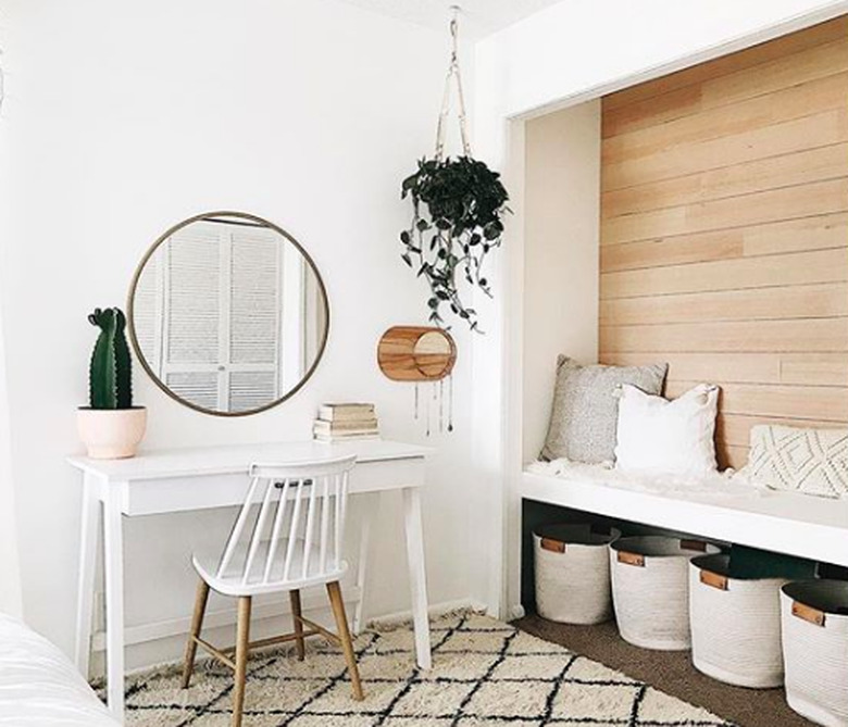 Minimal office space with white desk and ladderback chair and circular mirror