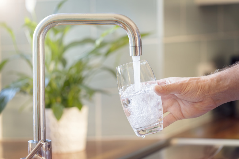 Filling up a glass with drinking water from kitchen tap