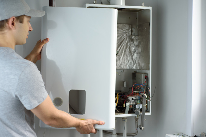 A man checks a gas boiler for home heating. Maintenance and repair of gas heating