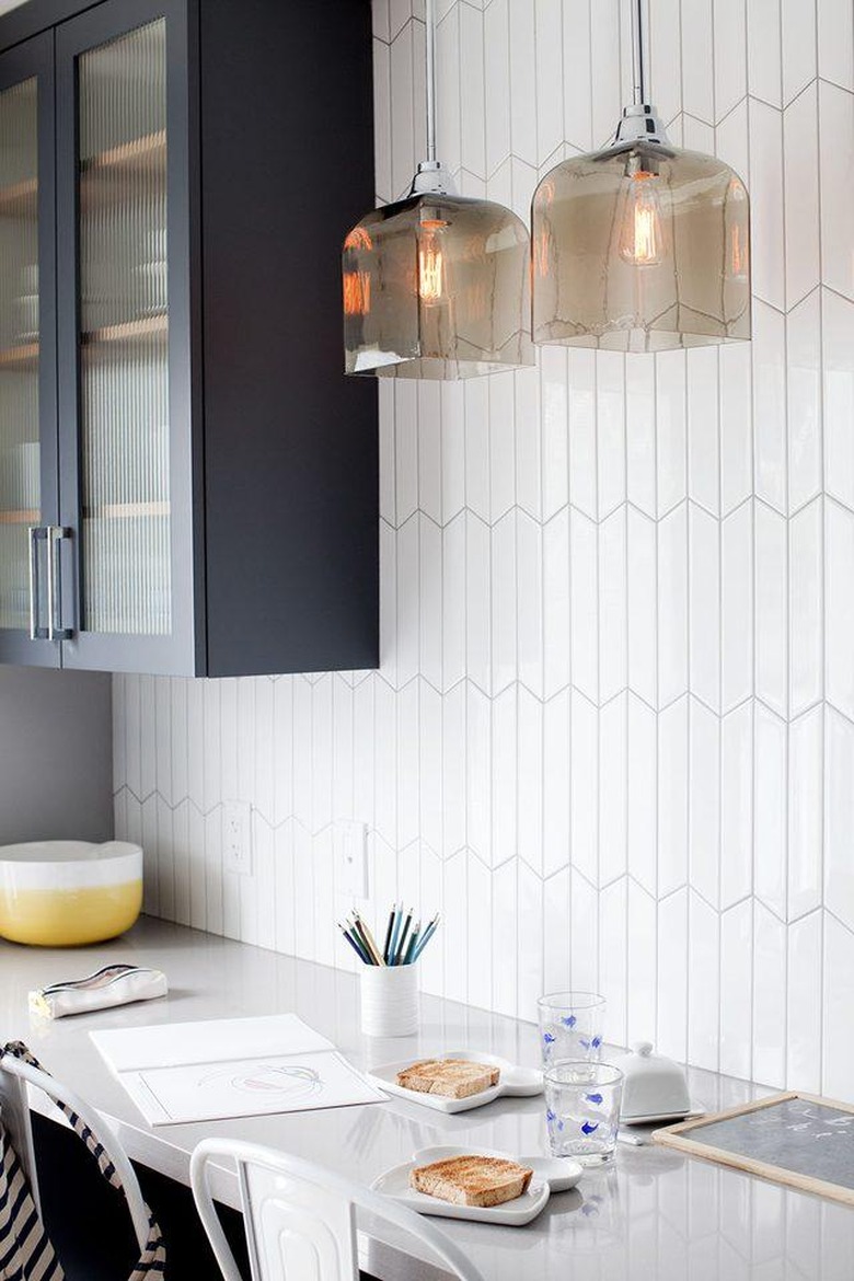 Minimal white tile art deco backsplash with pendant lights and blue cabinets