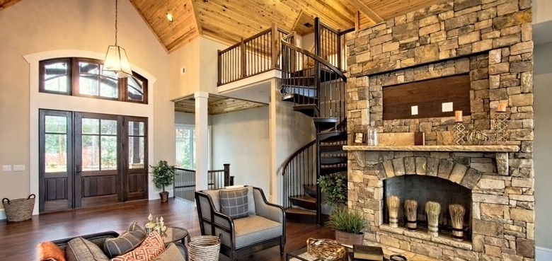 Black metal spiral staircase, yellow side chairs, brick wall.