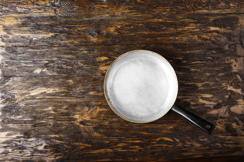 old aluminum frying pan on a wooden background.