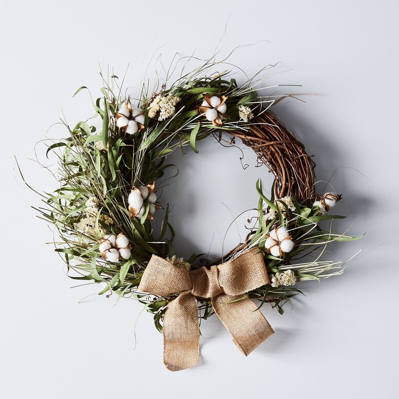 farmhouse Christmas decor with grapevine wreath with greenery, cotton buds, and burlap bow