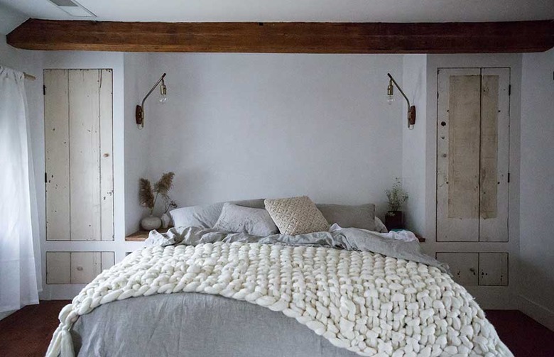 Scandinavian bedroom idea with Chunky knit blanket, wood closet doors, exposed bulb sconces