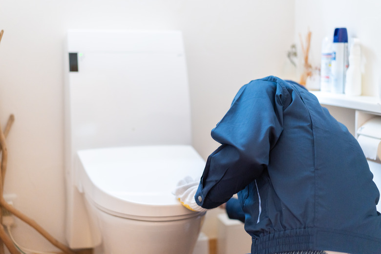 Technician doing toilet maintenance at home