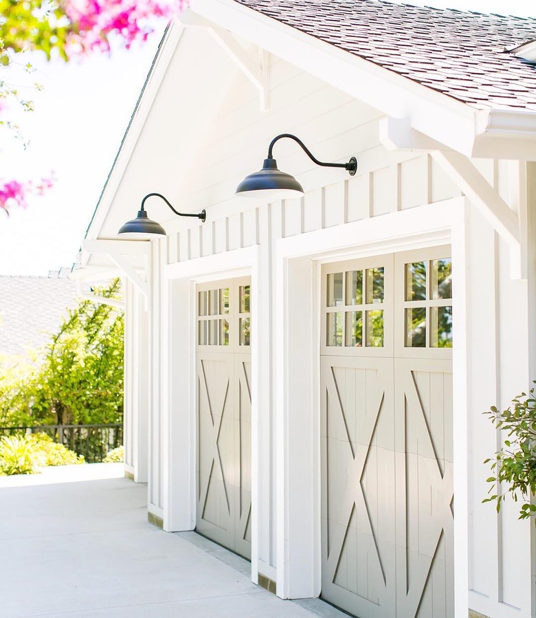 Cream barn garage doors with white exterior and black barn lights