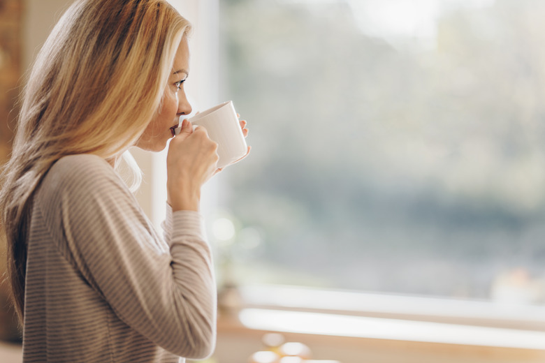 Profile view of pensive woman drinking morning coffee at home.