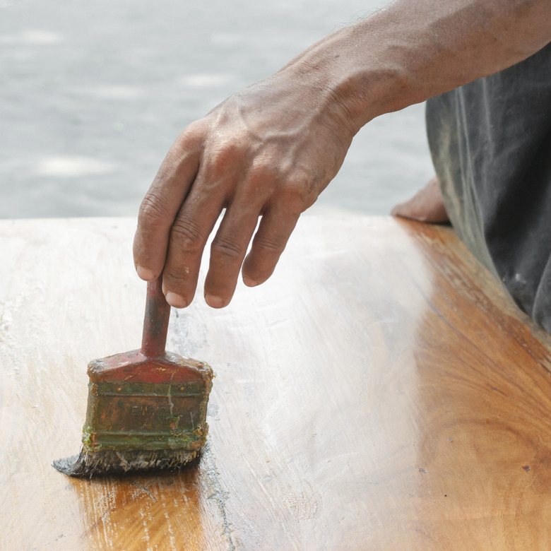 Varnishing antique wooden table using paintbrush