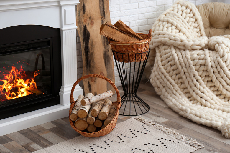 Wicker baskets with firewood and burning fireplace in cozy living room