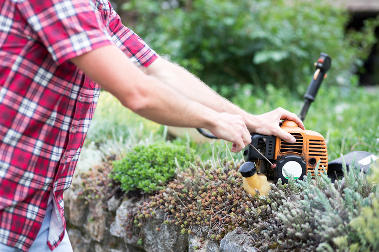 Close-up of a young man starting a string trimmer