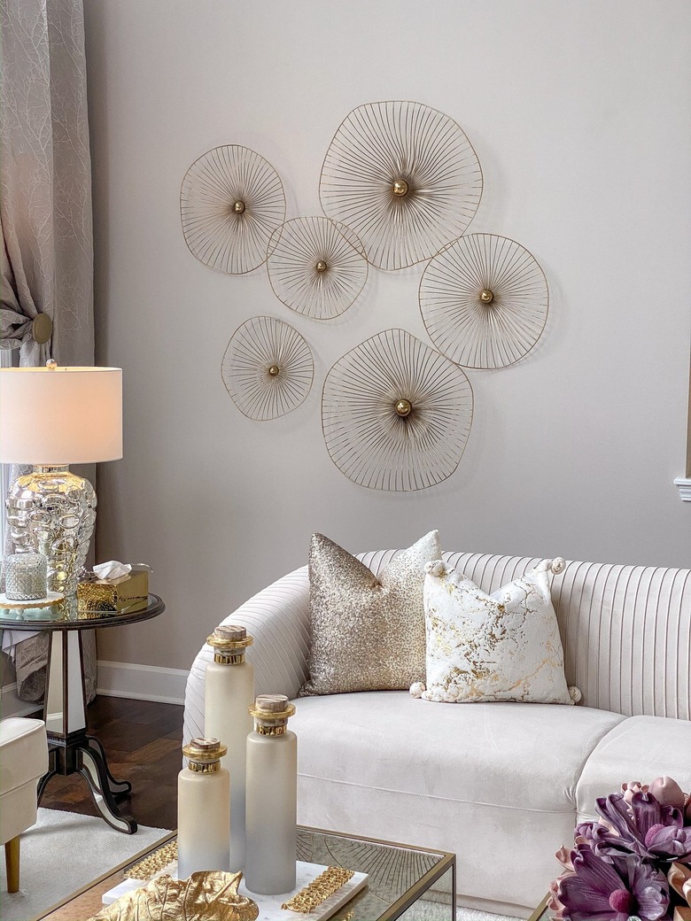 gold asymmetrical circle wall art behind white sofa